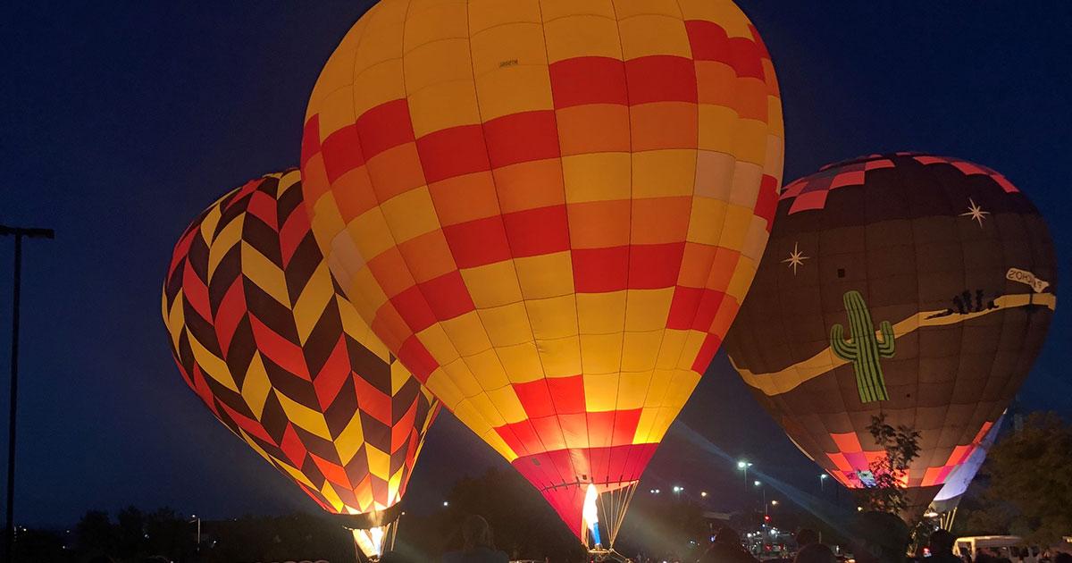 Three hot air balloon in full burn with their yellow and red tops glowing.